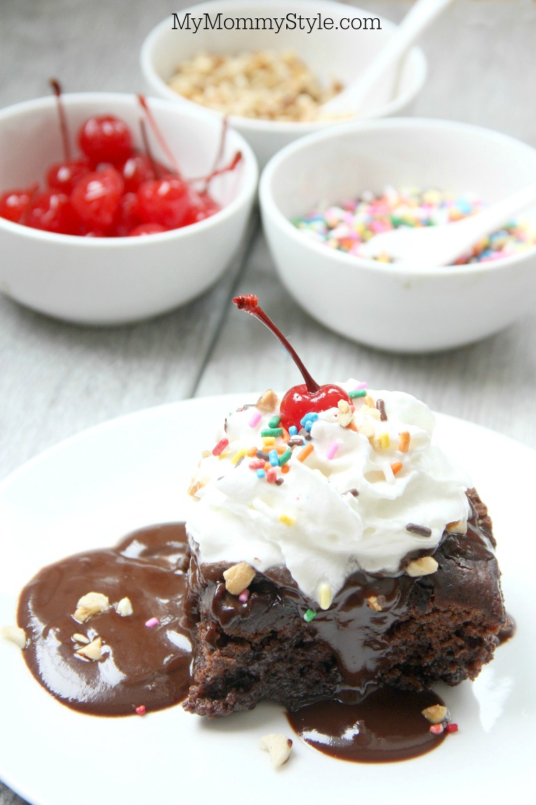 Crockpot hot fudge sundae dump cake topped with whipped cream, sprinkles and a cherry