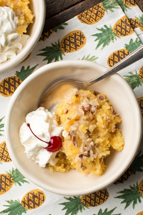 Crock pot pineapple coconut dump cake with whipped cream and a cherry on top