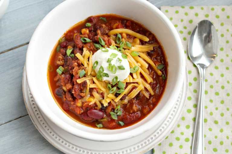Low Calorie meal prep bowl of turkey chili topped with cheese, sour cream and green onions. 